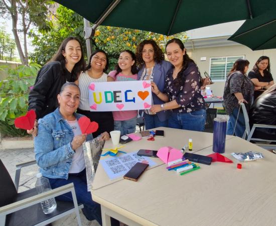 Participantes del taller de origami sostienen los productos que realizaron y sonríen frente a la cámara