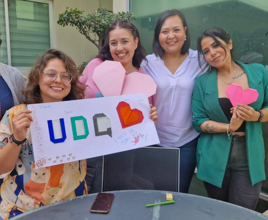 Participantes del taller de origami sostienen los productos que realizaron y sonríen frente a la cámara