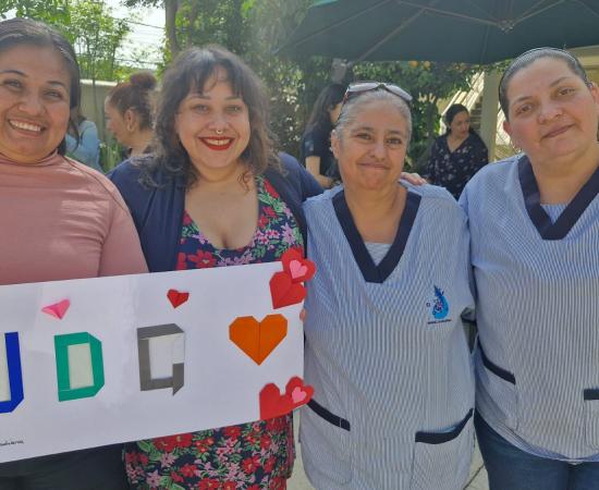 Participantes del taller de origami sostienen los productos que realizaron y sonríen frente a la cámara